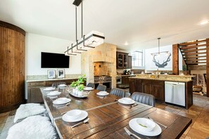A modern kitchen with a dining area, granite countertops, a stone fireplace, and a built-in oven. - Mountain View Rooftop Deck + Hot Tub, walk to Main st. Park City Ultimate Loft 4 (Park City)