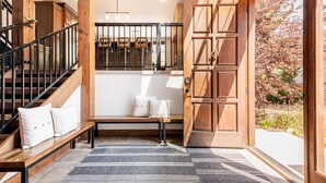 A wooden staircase, a bench, a door, and a view of the outside.