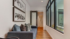 A hallway with a grey sofa, framed artwork, and a wooden floor. - Unbeatable Location, Hot Tub, Luxury Amenities & Year-Round Recreation! Park City Parkite 35 (Park City)