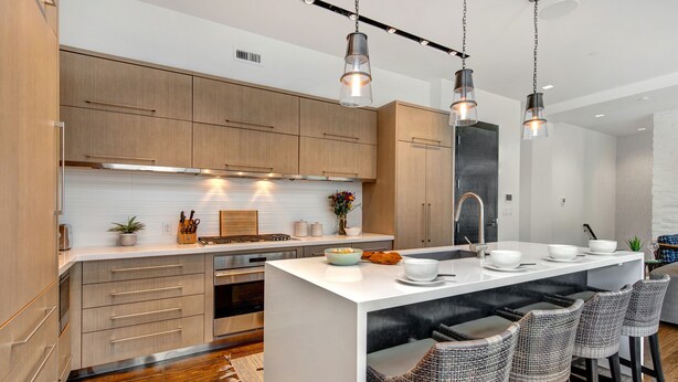 A modern kitchen with wooden cabinets, a central island with bar stools, pendant lighting, and a backsplash with a plant. - Unbeatable Location, Hot Tub, Luxury Amenities & Year-Round Recreation! Park City Parkite 35 (Park City)