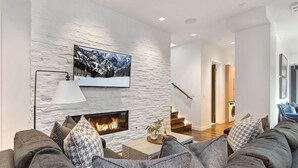 A modern living room with a fireplace, a mounted TV, and a staircase leading to another level. - Unbeatable Location, Hot Tub, Luxury Amenities & Year-Round Recreation! Park City Parkite 35 (Park City)