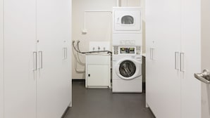 A laundry room with a stacked washer and dryer, a small table with a sink, and a vent pipe on the ceiling. - Padstow Park Hotel (Padstow)