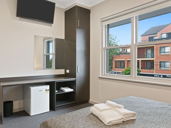 A hotel room with a large window, a minibar, a built-in desk, and a mirror. - Padstow Park Hotel (Padstow)