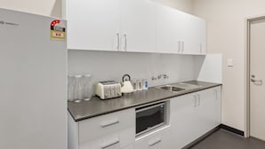 A modern kitchen with white cabinets, a built-in microwave, a toaster, and a sink. - Padstow Park Hotel (Padstow)