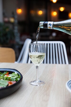 A bottle of white wine being poured into a glass on a wooden table. - Padstow Park Hotel (Padstow)