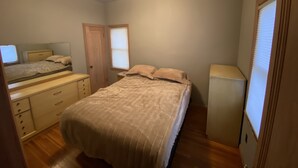 Ein Schlafzimmer mit Bett, Schminktisch, Spiegel und Deckenleuchte.