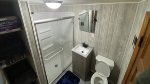 Ein kleines Badezimmer mit Dusche, Toilette und Waschbecken.