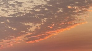 Ein Sonnenuntergang über einer ebenen Landschaft mit einem Fluss und fernen Hügeln.