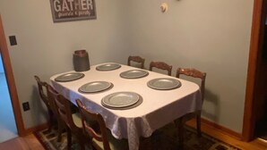 Ein Esszimmer mit gedecktem Tisch für sechs Personen, einem aufgehängten Hirschgeweih an der Wand und einem Schild mit der Aufschrift 'Gather friends & family'.