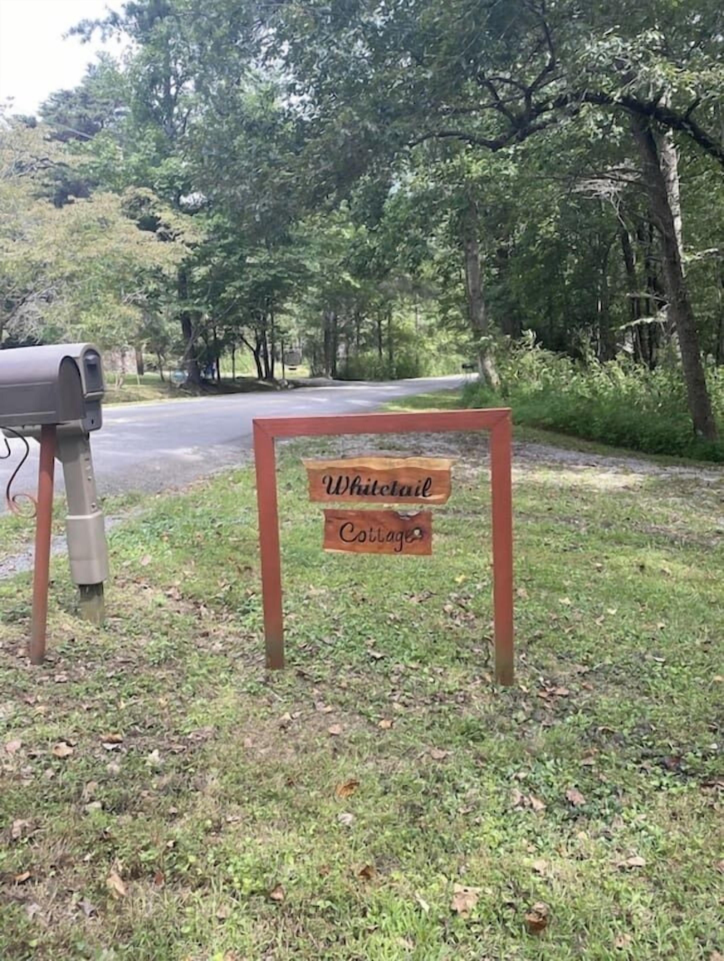 A mailbox and a wooden sign that reads "Whitetooth Cottages."