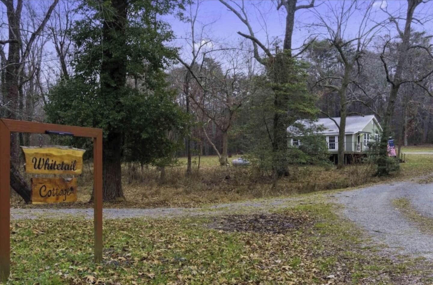 A signboard for Whitetail Cottages, a house, and a forested area.