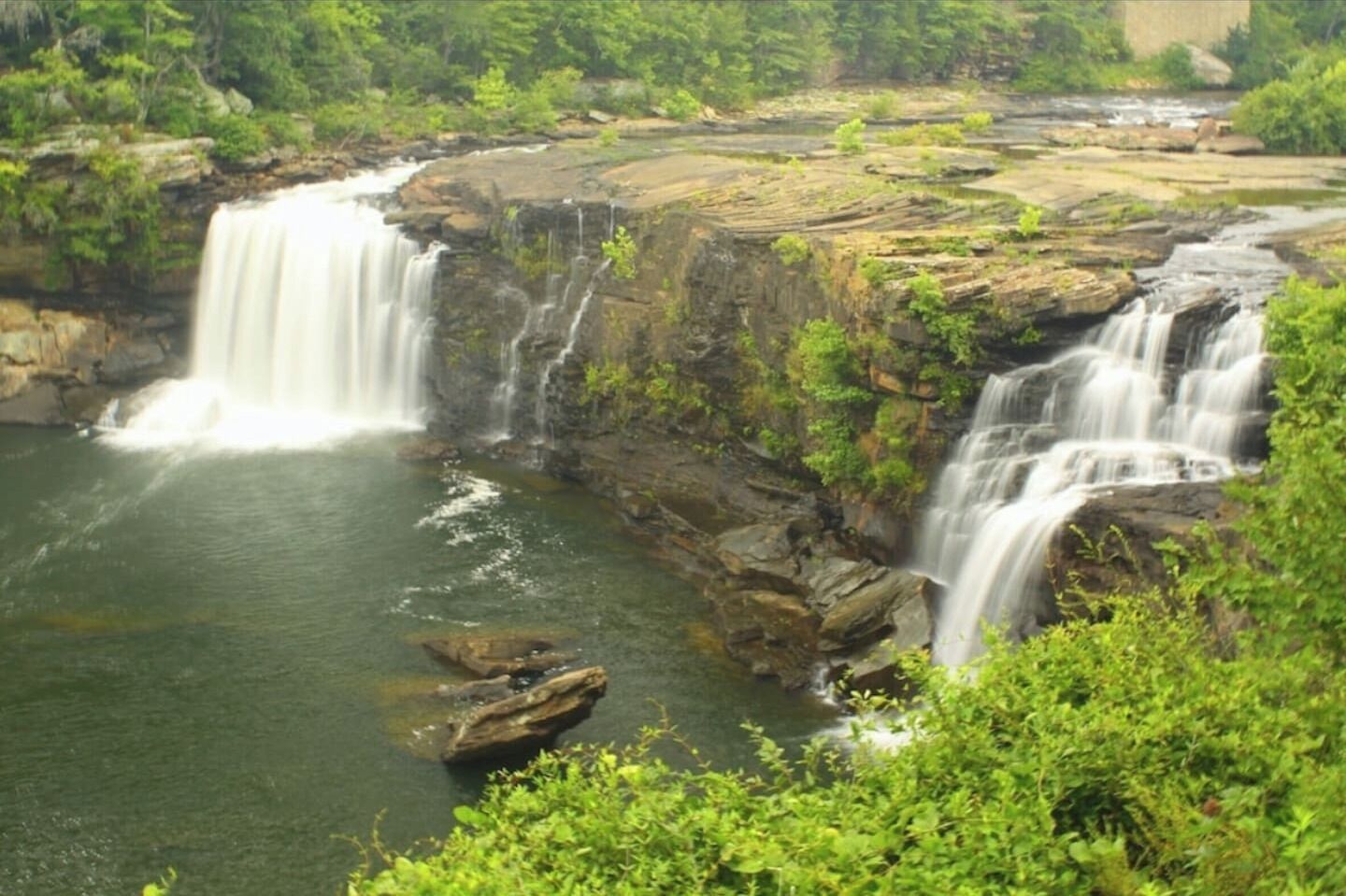 Une cascade d’eau se déversant sur un terrain rocheux, entourée d’une végétation luxuriante.