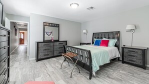 A bedroom with a bed, bedside tables, a dresser, and a chair. - The Paris- Colorful 3BEDROOM 2BATH SFH w/Heated POOL Available  (Houston)