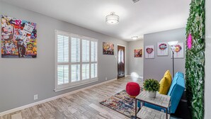 A modern interior with a large window, a colorful rug, and various artworks on the walls. - The Paris- Colorful 3BEDROOM 2BATH SFH w/Heated POOL Available  (Houston)