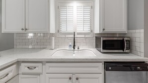 A kitchen with white cabinets, a double sink, a microwave, and a dishwasher. - The Paris- Colorful 3BEDROOM 2BATH SFH w/Heated POOL Available  (Houston)