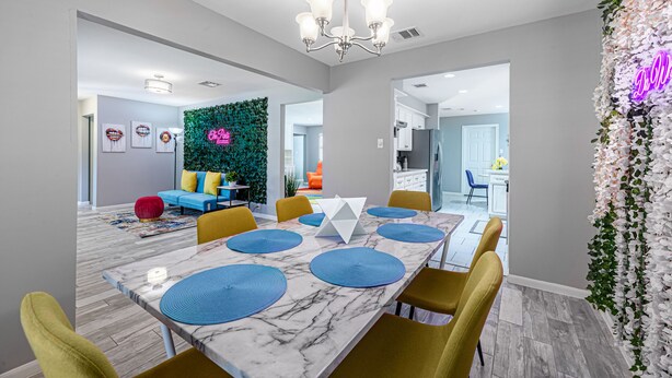 A modern dining area with a marble table, yellow chairs, and blue placemats. - The Paris- Colorful 3BEDROOM 2BATH SFH w/Heated POOL Available  (Houston)