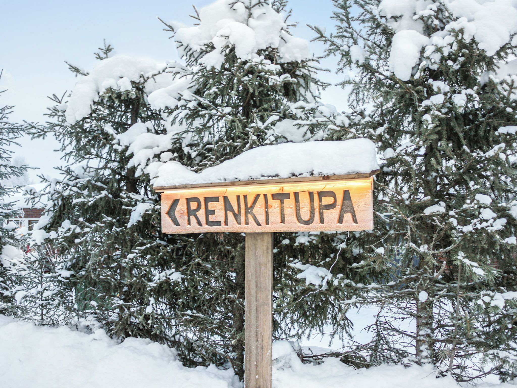 A wooden sign with the name 'RENKITUPA' in capital letters, surrounded by snow-covered trees.
