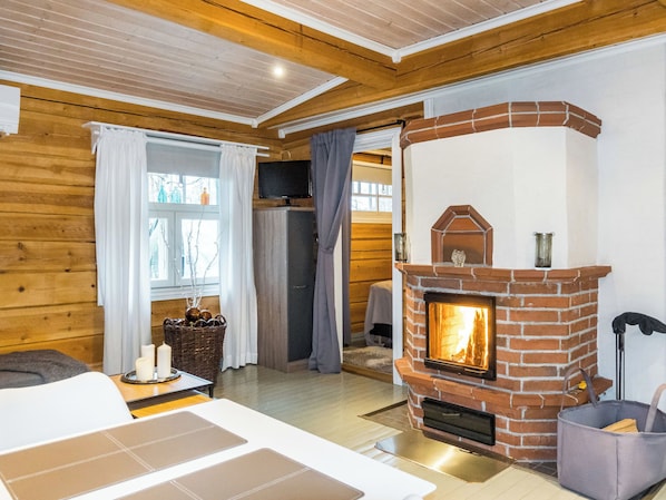 A cozy room with a brick fireplace, wooden walls, and a modern sofa. - Renkitupa by Interhome (Rovaniemi)