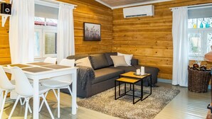 Una habitación acogedora con elementos de madera, un sofá, una mesita pequeña y una mesa de comedor con sillas.