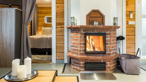 Una habitación acogedora con chimenea de ladrillo, una cama y una pequeña mesa con velas.