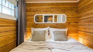Un dormitorio de cabaña de madera con una cama, almohadas y un espejo en la pared.