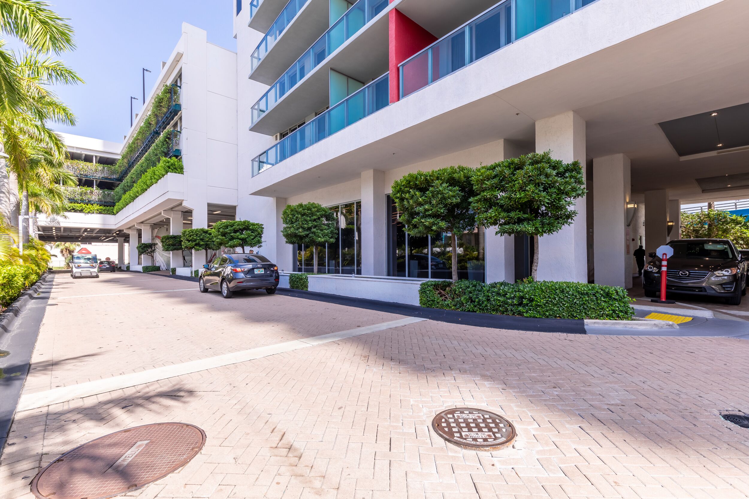 Un edificio moderno con techo plano, ventanas amplias y un paseo pavimentado.