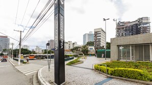 Eine Straßenscharte mit einem auffälligen schwarzen Schild, einer Straßenbahn und modernen Gebäuden im Hintergrund.