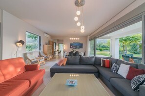 Una sala de estar moderna con un sofá modular grande, una mesa de centro y un comedor con sillas.