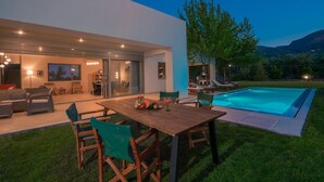 Une maison moderne dotée d’une piscine, d’un espace salon extérieur et d’un coin repas.