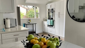 Een moderne keuken met witte kastjes, een zwart aanrecht en een fruitschaal op het eiland.