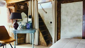 Una habitación con una escalera de madera, una mesa con una lámpara y una silla.