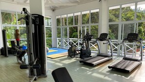Ett gym med konditionsmaskiner, styrketräningsutrustning och ett område med yogamattor.