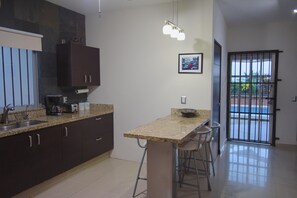 A modern kitchen with granite countertops, dark cabinets, a built-in oven, and a bar area with stools. - Private house, pool, bbq and jacuzzi!! (Mazatlán)