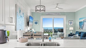 Una cocina moderna con un gran ventanal, un comedor y un salón con vistas a la costa.