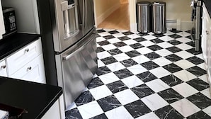 A kitchen with a black and white checkered floor, stainless steel appliances, and white cabinetry. - Canary Lodge - Berkshires Mountain Retreat - 6 Guests (West Stockbridge)