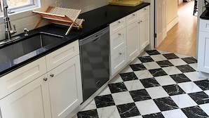A kitchen with white cabinets, a black and white checkered floor, and a window with a view of trees. - Canary Lodge - Berkshires Mountain Retreat - 6 Guests (West Stockbridge)