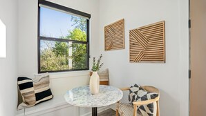 Una habitación con un ventanal grande, una mesa redonda de mármol, una silla y dos paneles de madera en la pared.