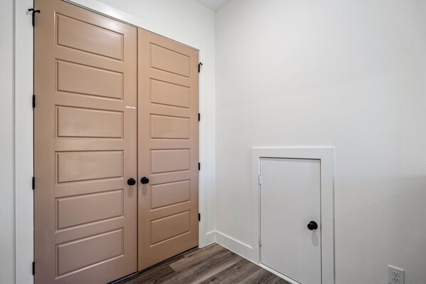 Un couloir avec une porte double de couleur beige et une porte simple de couleur blanche.