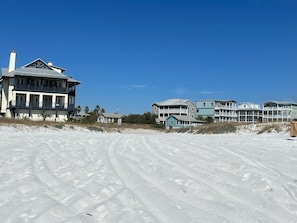 A beachfront property with multiple buildings, including a large house with a balcony and a smaller structure.