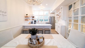 Uma cozinha moderna com ilha central, armários brancos e um lustre.