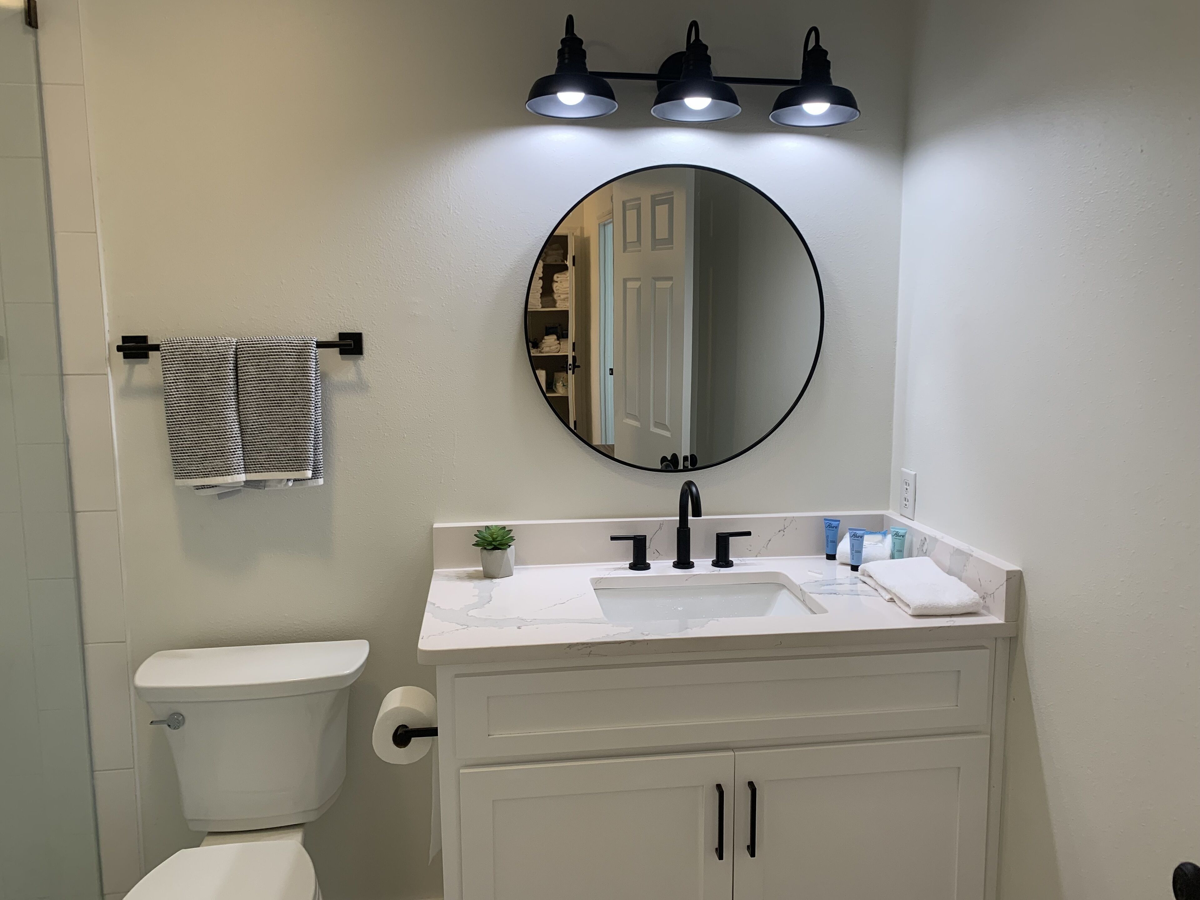 A bathroom with a toilet, sink, mirror, and towel rack.