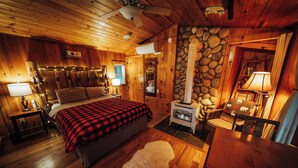 Ein gemütliches Blockhauszimmer mit Bett, Kamin, Holzwänden und einer Wand aus Stein.
