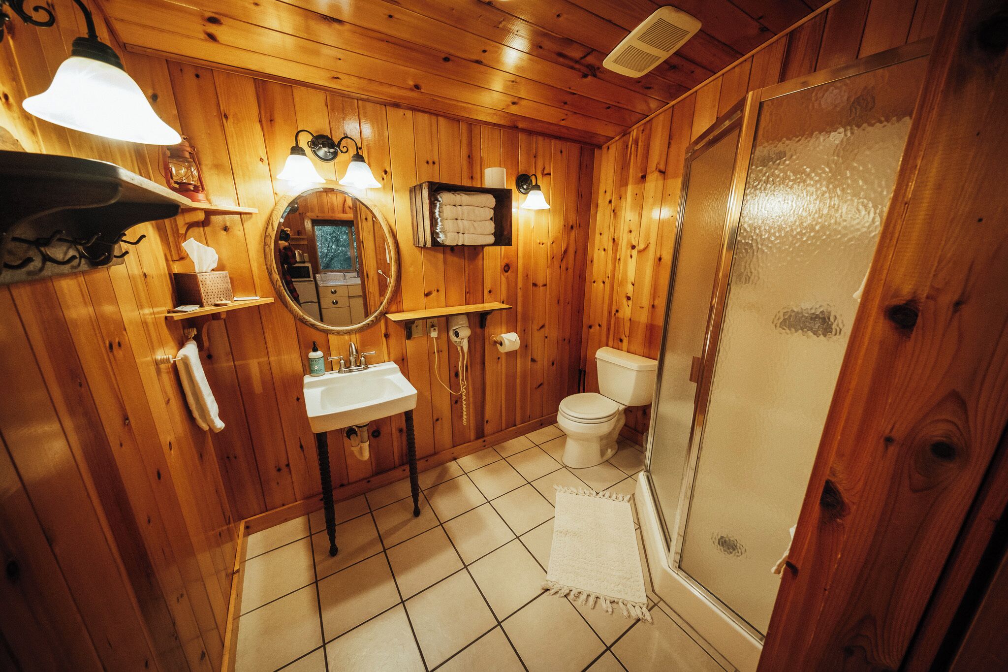 Un baño con paneles de madera, un lavabo, un espejo, un inodoro y una ducha.