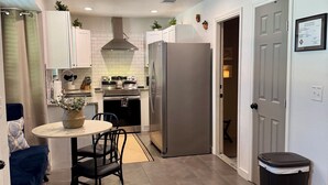 Une cuisine moderne avec des meubles blancs, un réfrigérateur en acier inoxydable et un coin repas comprenant une table et des chaises.
