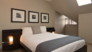 Un dormitorio con cama, mesitas de noche, un calentador de pared y tres cuadros enmarcados.