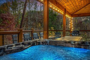 Un bain à remous avec une terrasse en bois, entouré de chaises et d’un barbecue.