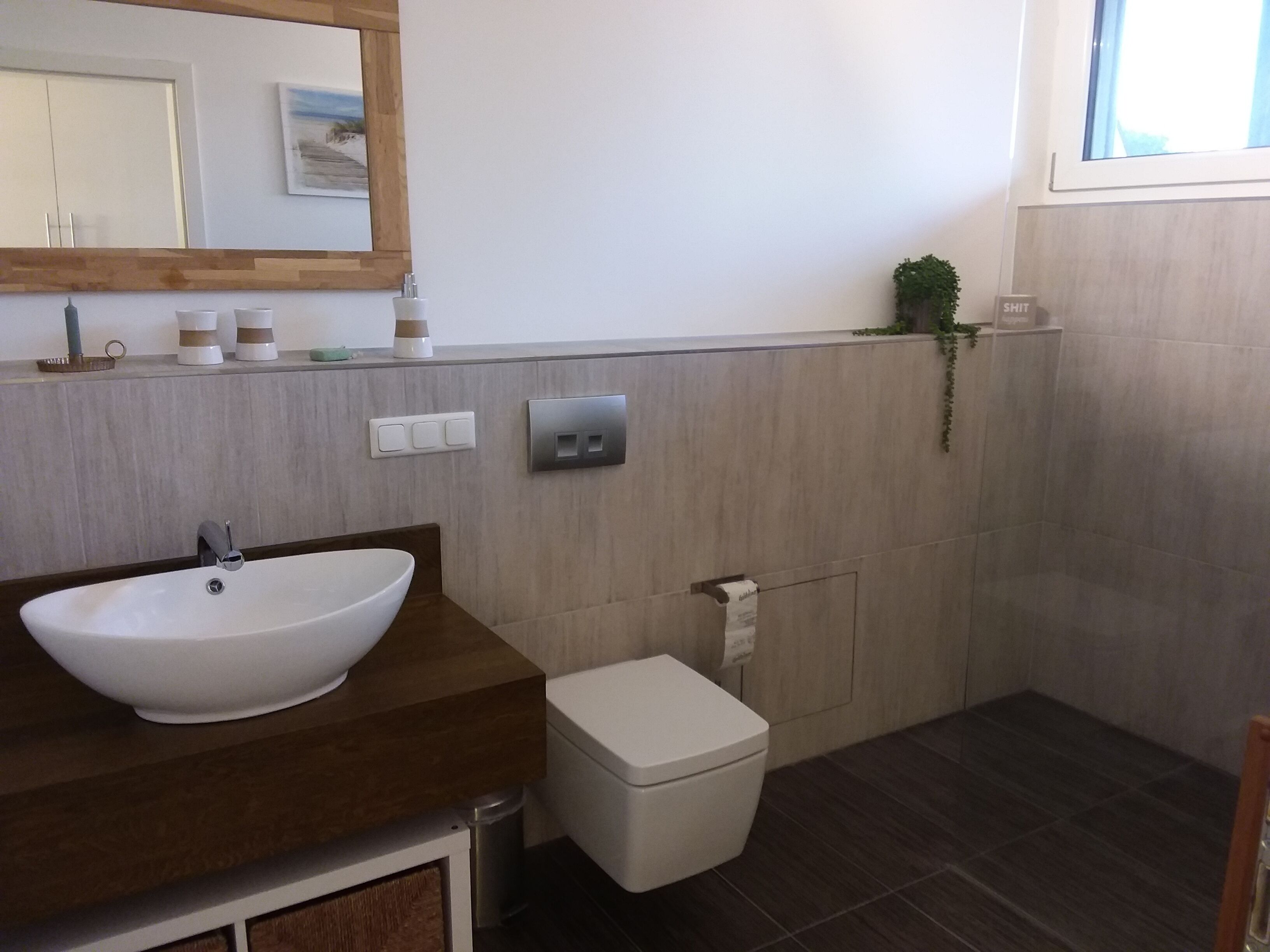 Et badeværelse med en hvid vask, toilet og spejl.