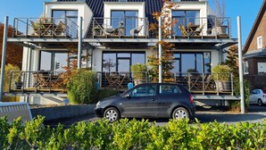 A two-story house with a balcony and a car parked in front. - Front row, more sea is not possible! (Haffkrug)