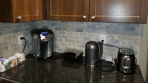 Eine Küche mit Holzausstattung, einer Kaffeemaschine, einem Wasserkocher und einem Toaster auf einer Granitarbeitsplatte.