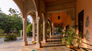 Un paseo techado con columnas, plantas en macetas y suelo a cuadros.